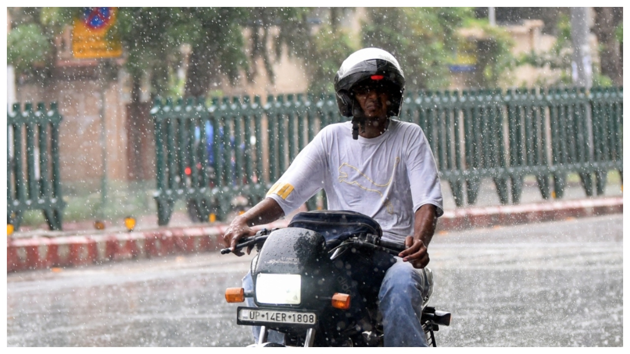 बारिश में बाइक से गुजरता युवक